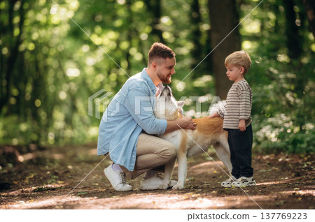 Positive facial expression, sitting. Father with son and dog are in the forest 137769223
