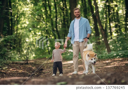 Free time, having a walk, wellness. Father with son and dog are in the forest 137769245