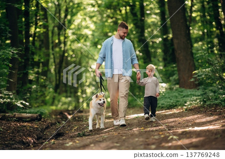 Free time, having a walk, wellness. Father with son and dog are in the forest Free time, having a walk, wellness. Father with son and dog are in the forest 137769248