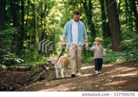 Free time, having a walk, wellness. Father with son and dog are in the forest 137769250