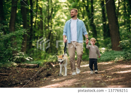 Free time, having a walk, wellness. Father with son and dog are in the forest 137769251