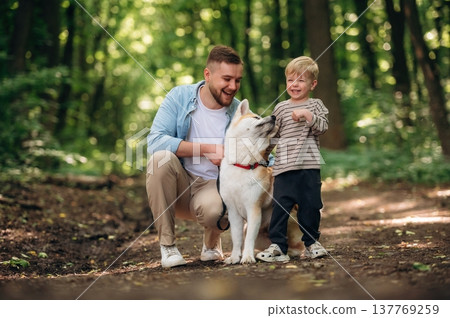 Boy is laughing. Father with son and dog are in the forest 137769259