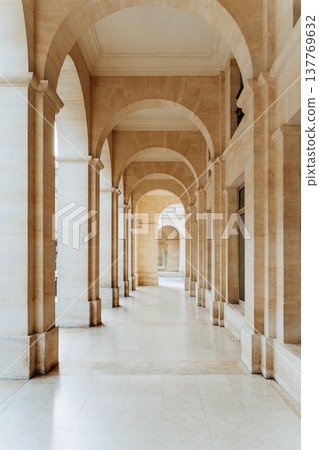 Elegant stone arcade with repeating arches and columns forming a symmetrical corridor Elegant stone arcade with repeating arches and columns forming a symmetrical corridor 137769632