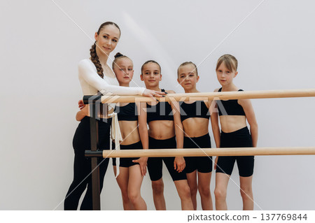 Just standing and taking a break. Trainer is teaching girls ballet dancing Just standing and taking a break. Trainer is teaching girls ballet dancing 137769844
