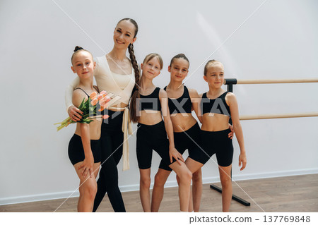 Smiling, standing and posing. Trainer is teaching girls ballet dancing Smiling, standing and posing. Trainer is teaching girls ballet dancing 137769848