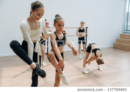 Helping, rehearsal process. Trainer is teaching girls ballet dancing Helping, rehearsal process. Trainer is teaching girls ballet dancing 137769865
