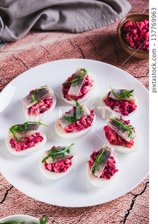 Eggs delived with vegetable salad, a piece of herring and arugula on a plate on the table vertical view Eggs delived with vegetable salad, a piece of herring and arugula on a plate on the table vertical view 137769963