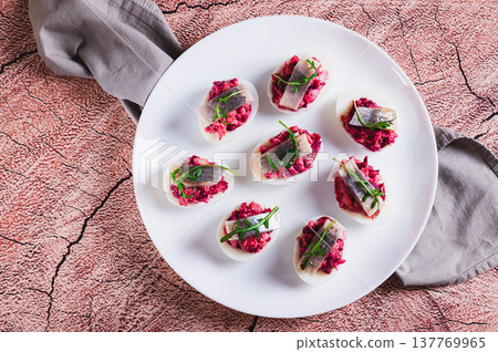 Close up of egg halves stuffed with herring under a fur coat on a plate on the table top view 137769965