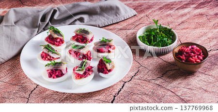 Egg halves stuffed with herring under a fur coat on a plate on the table web banner 137769968