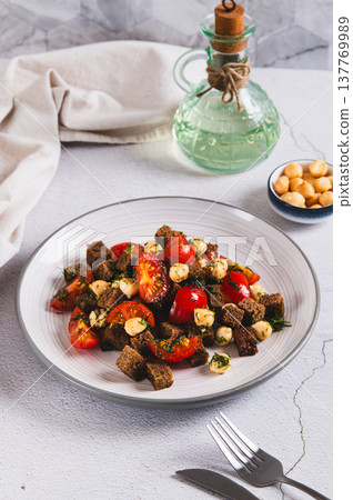 A mixture of tomatoes, cheese and rye croutons on a plate on the table vertical view A mixture of tomatoes, cheese and rye croutons on a plate on the table vertical view 137769989