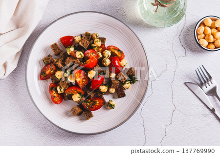 Salad of rye bread, cherry tomatoes and smoked cheese on a plate on the table top view 137769990