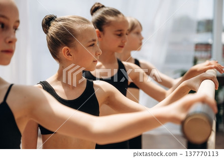 Four people. Girls practicing ballet indoors in the class Four people. Girls practicing ballet indoors in the class 137770113