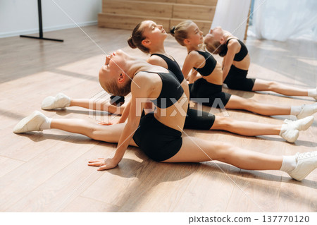 On the floor. Girls practicing ballet indoors in the class 137770120