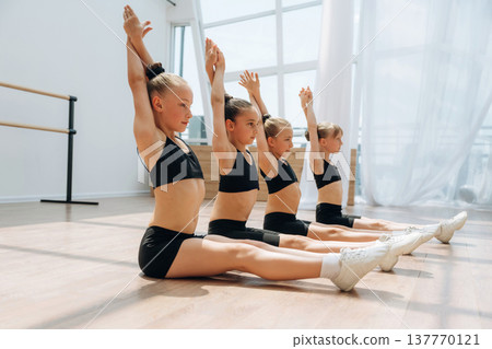 On the floor. Girls practicing ballet indoors in the class 137770121