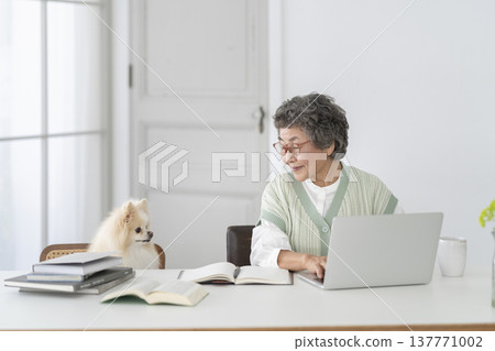 A senior woman who works at a desk and her beloved dog 137771002
