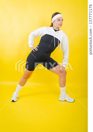 Woman stretching in sporty jumpsuit and cropped hoodie Woman stretching in sporty jumpsuit and cropped hoodie 137771176