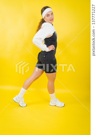 Young woman posing in athletic wear on yellow background 137771227