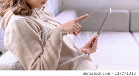 一個操作帶沙發的平板電腦的女人 137771318
