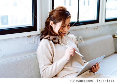 A woman creating art on a tablet. A woman creating art on a tablet. 137771353