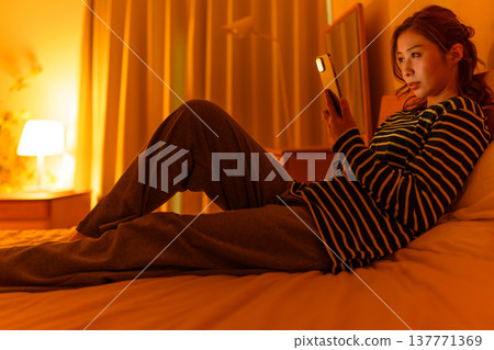 A woman staring at her smartphone in bed A woman staring at her smartphone in bed 137771369