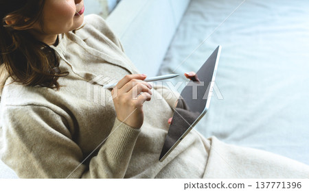A woman's hands holding a tablet and pen. A woman's hands holding a tablet and pen. 137771396