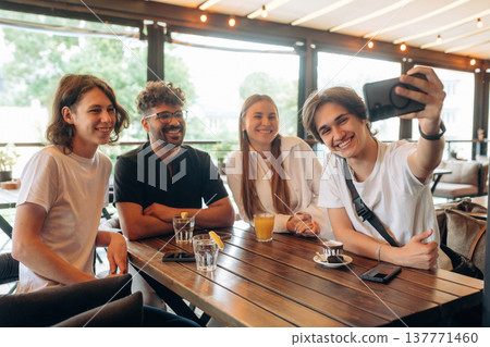 Four people are smiling, doing selfie. Group of young friends are in the cafe restaurant Four people are smiling, doing selfie. Group of young friends are in the cafe restaurant 137771460
