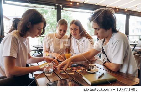 Playing the game at the table. Group of young friends are in the cafe restaurant Playing the game at the table. Group of young friends are in the cafe restaurant 137771485