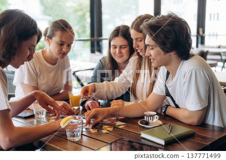 Wellness, playing card game. Group of young friends are in the cafe restaurant Wellness, playing card game. Group of young friends are in the cafe restaurant 137771499