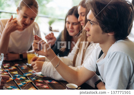 Wellness, playing card game. Group of young friends are in the cafe restaurant Wellness, playing card game. Group of young friends are in the cafe restaurant 137771501