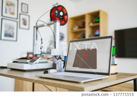 A modern 3D printer is connected to a laptop displaying a 3D model, ready for creation A modern 3D printer is connected to a laptop displaying a 3D model, ready for creation 137771553