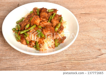 spicy stir fried slice yard long bean with crispy pork and lemon grass in curry sauce on rice in plate spicy stir fried slice yard long bean with crispy pork and lemon grass in curry sauce on rice in plate 137771665