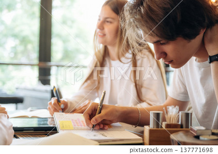 Students are working on the project. Group of young friends are in the cafe restaurant Students are working on the project. Group of young friends are in the cafe restaurant 137771698