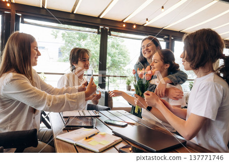Giving the flowers, celebrating. Group of young friends are in the cafe restaurant Giving the flowers, celebrating. Group of young friends are in the cafe restaurant 137771746