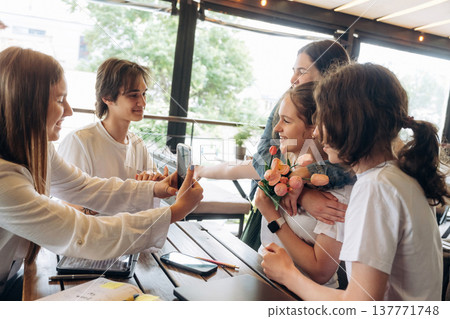 Giving the flowers, celebrating. Group of young friends are in the cafe restaurant Giving the flowers, celebrating. Group of young friends are in the cafe restaurant 137771748