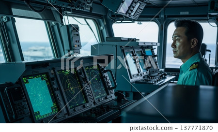 Asian naval officer monitoring radar systems and navigation equipment on modern warship bridge during maritime operations 137771870