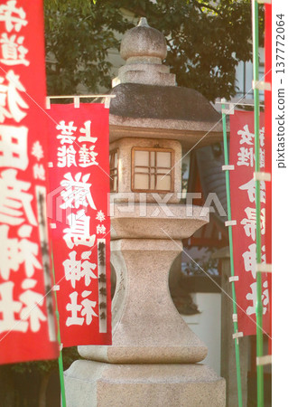 Stone lanterns and banners at a Japanese shrine 137772064