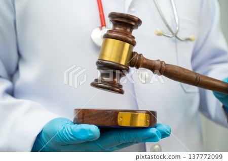 Asian doctor holding court hammer for and crime law justice, forensic medicine. 137772099