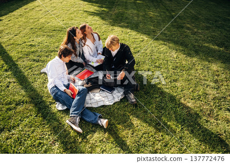 Sitting on the ground. Friends students are together outdoors Sitting on the ground. Friends students are together outdoors 137772476