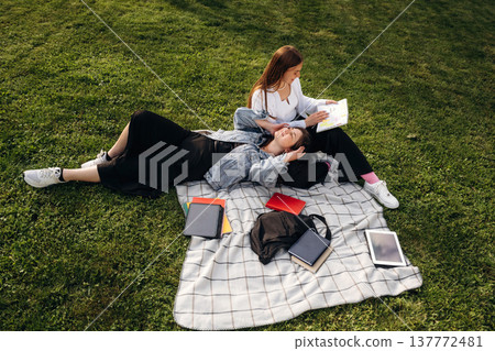 Two girls students are on the grass, outdoors 137772481