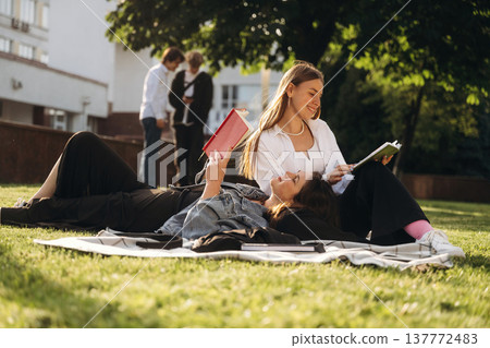 On the ground, lying down. Group of students are near university together On the ground, lying down. Group of students are near university together 137772483