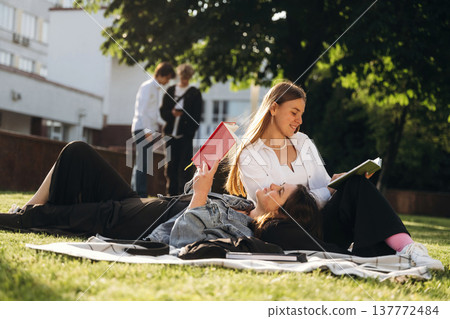 On the ground, lying down. Group of students are near university together On the ground, lying down. Group of students are near university together 137772484