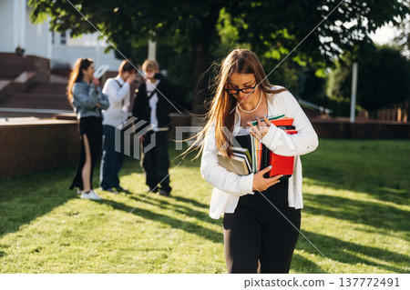 Bunch of notepads in hands of a girl. Group of students are near university together 137772491