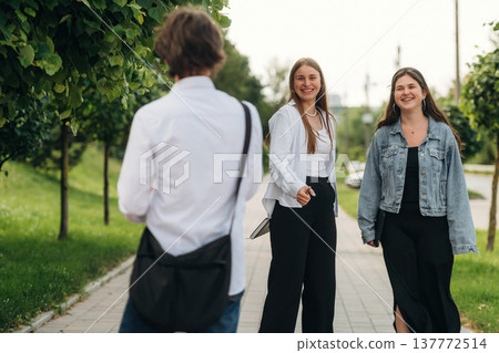 Walking on the pathway. Friends students are together outdoors 137772514