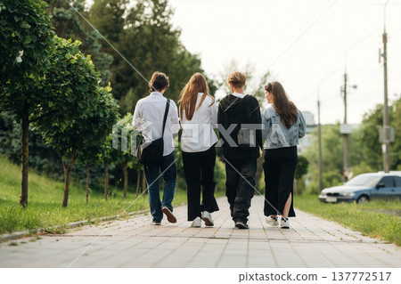 Walking on the pathway. Friends students are together outdoors Walking on the pathway. Friends students are together outdoors 137772517