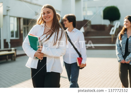 Toothy smile, standing. Group of students are near university together Toothy smile, standing. Group of students are near university together 137772532