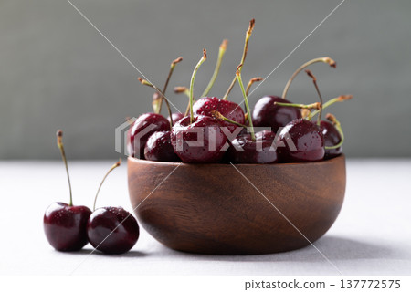 Fresh red cherries with water droplets in a wooden bowl 137772575