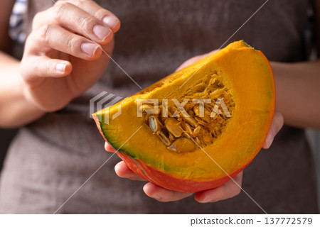 Hands holding sliced orange Kuri squash (Hokkaido pumpkin) prepare for cooking Hands holding sliced orange Kuri squash (Hokkaido pumpkin) prepare for cooking 137772579