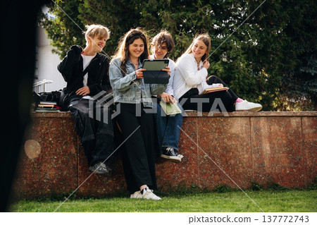 Looking at digital tablet. Group of students are near university together Looking at digital tablet. Group of students are near university together 137772743