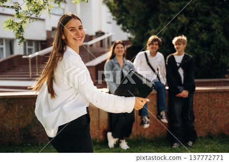 Girl is standing in front of her friends. Group of students are near university together 137772771