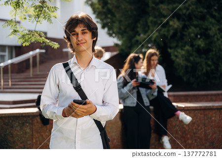 Young guy is standing in front of his friends. Group of students are near university together 137772781